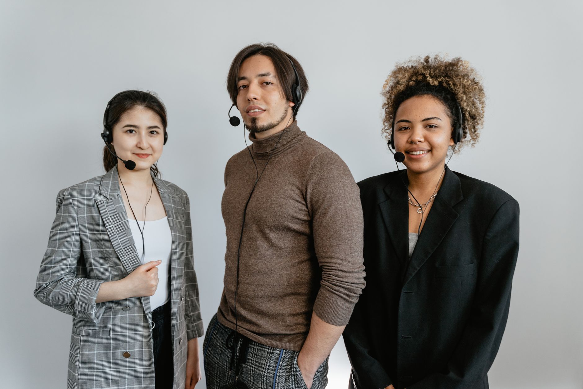 Three diverse customer support representatives wearing headsets and standing together.