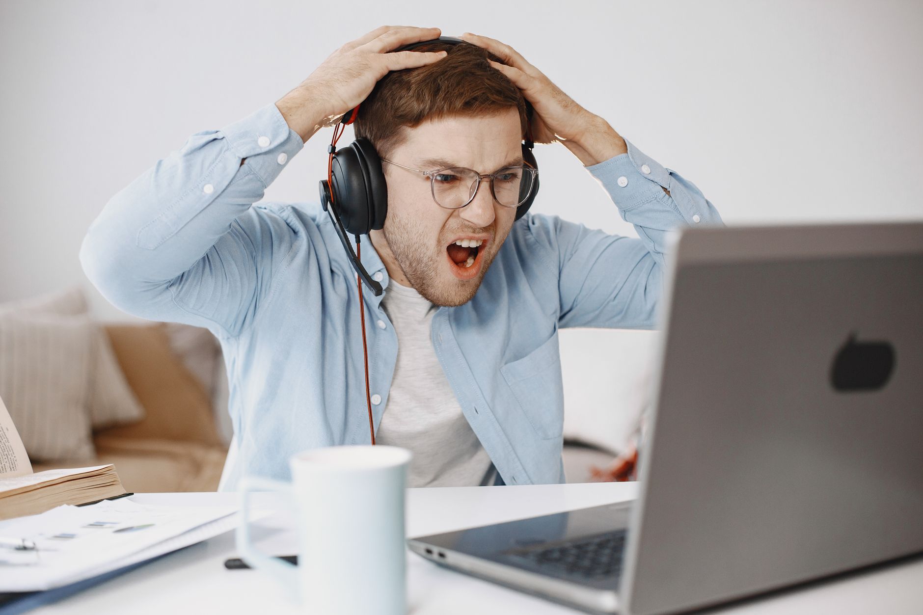 Man experiencing frustration at home office while working on laptop.