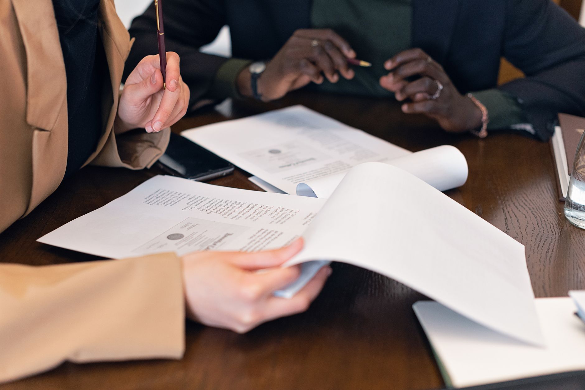 Close-up of professionals reviewing documents during a business meeting in an office setting.